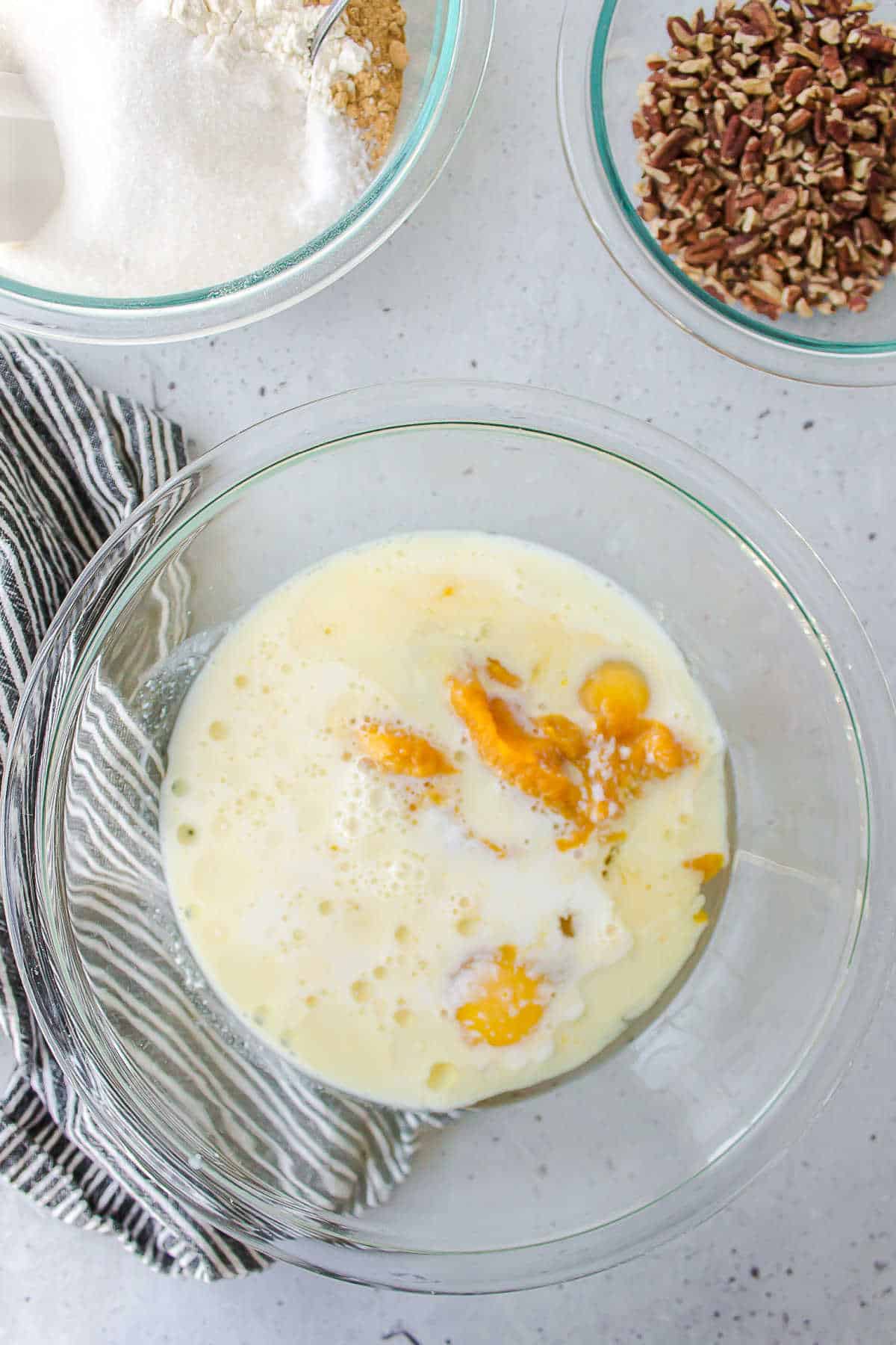 Glass mixing bowl with eggs buttermilk and pumpkin in it. 