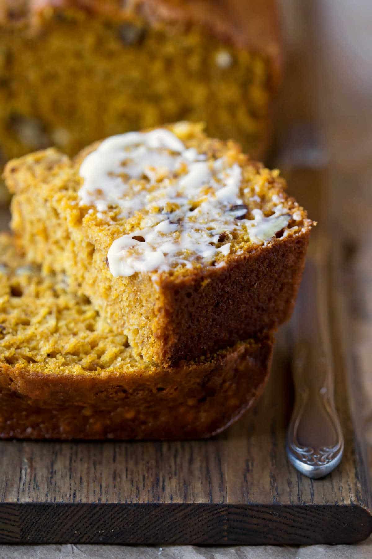 Half of a buttered slice of buttermilk pumpkin bread on a slice of pumpkin bread.