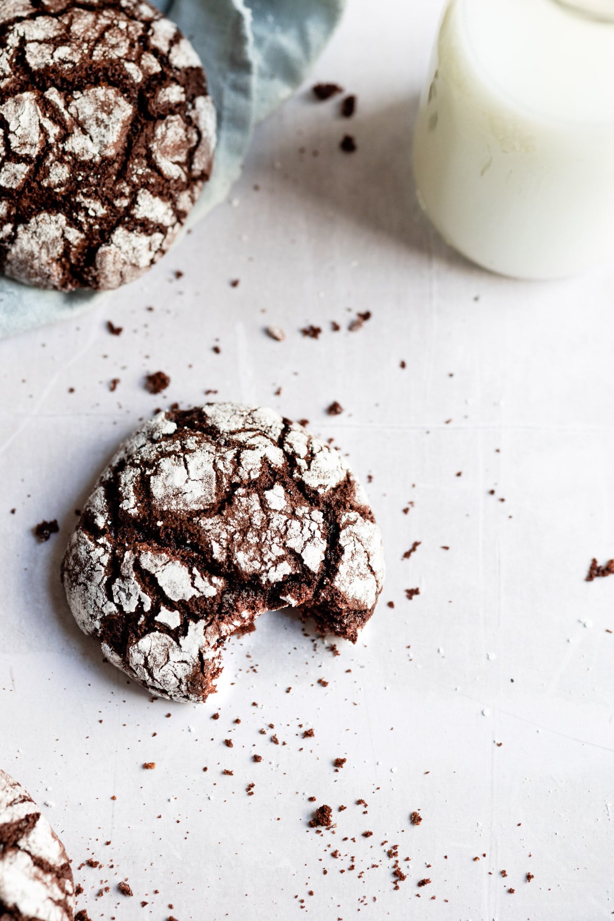 A chocolate crinkle cookie with a bite out of it by a glass of milk.