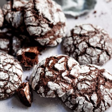 Chocolate crinkle cookies stacked around on each other.