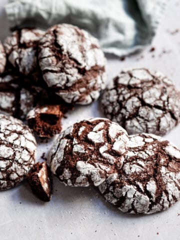 Chocolate crinkle cookies stacked around on each other.