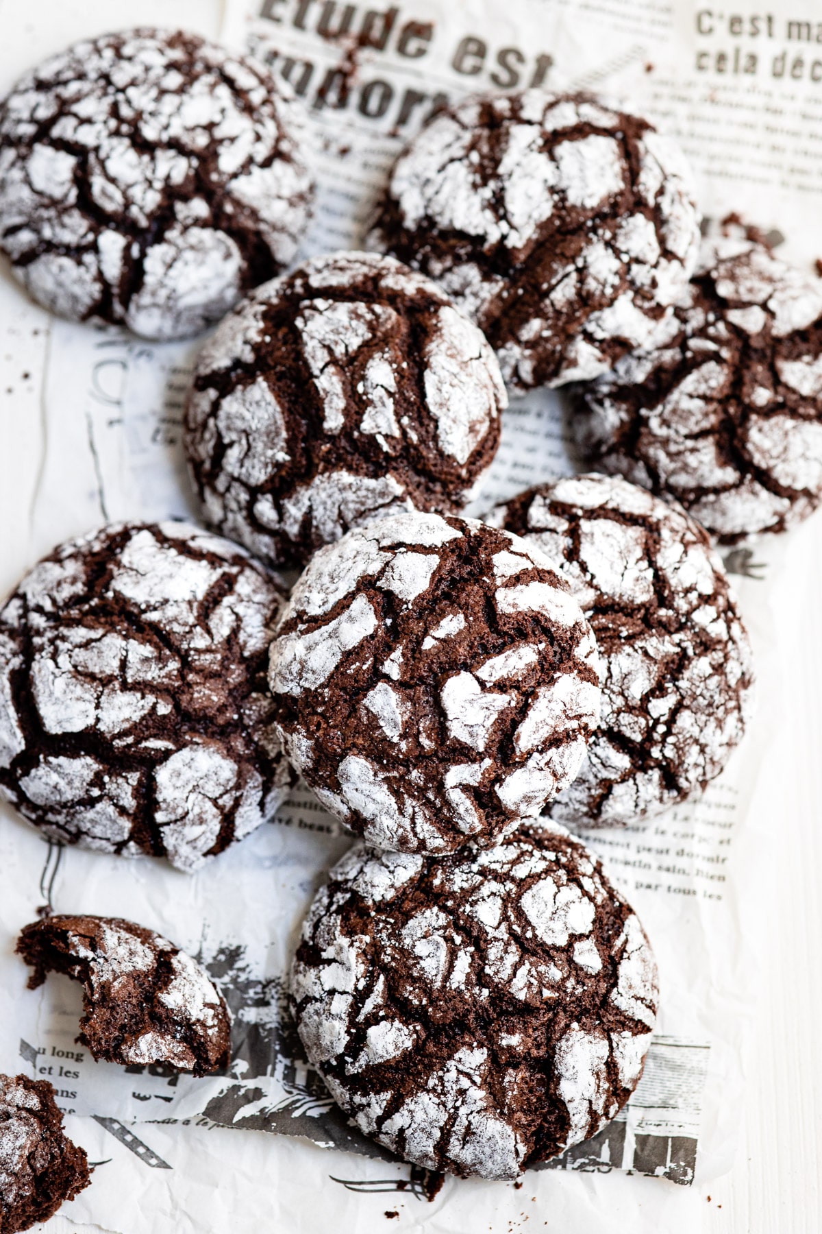 Stack of chocolate crinkle cookies on newsprint.