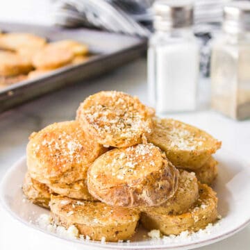 Parmesan potatoes on a white plate next to salt and pepper shakers.