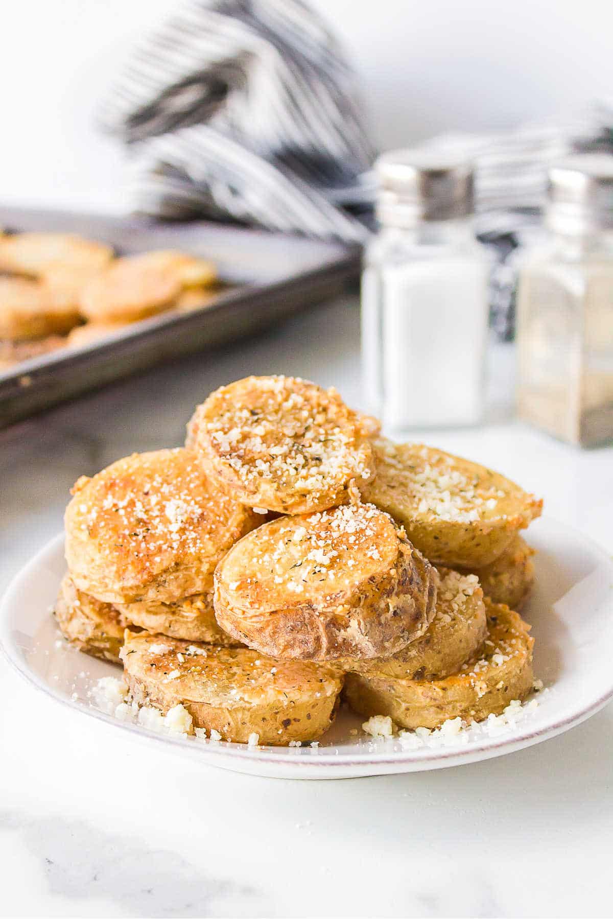 Parmesan potatoes on a white plate next to salt and pepper shakers.