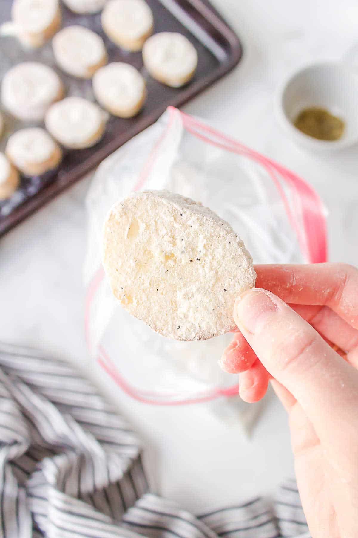 Slice of potato coated with flour being taken from a baggie. 