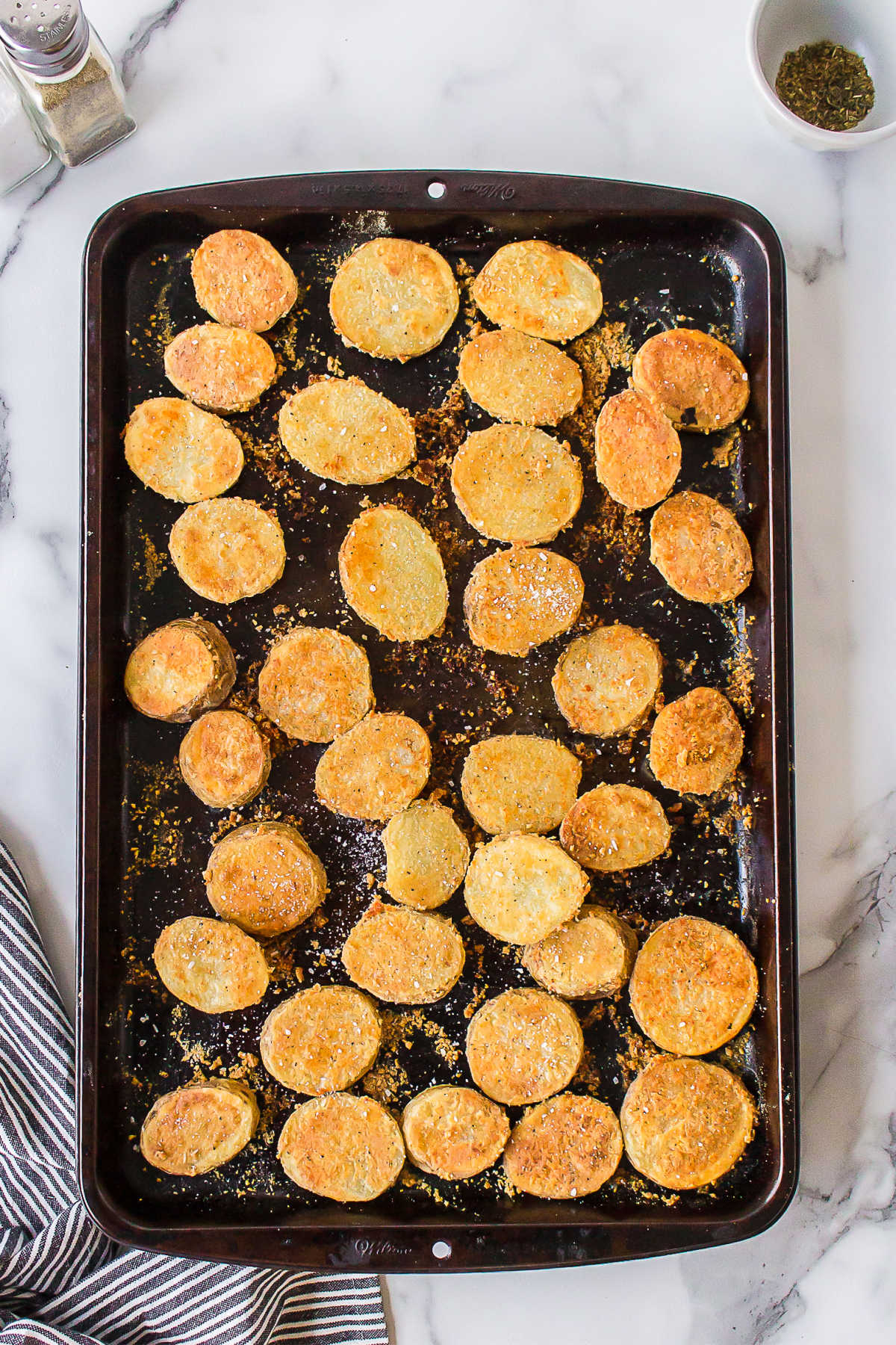 Baked slices of parmesan potatoes in a jelly roll pan. 