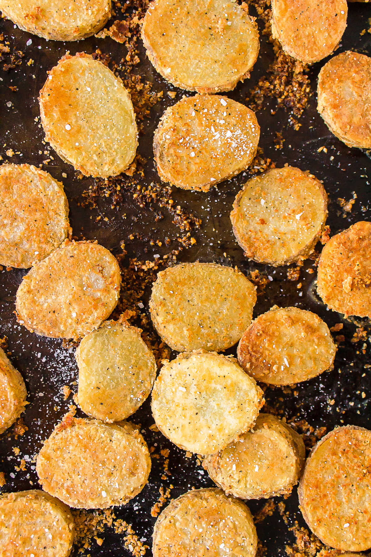 Close up photo of baked parmesan potatoes on a baking sheet. 