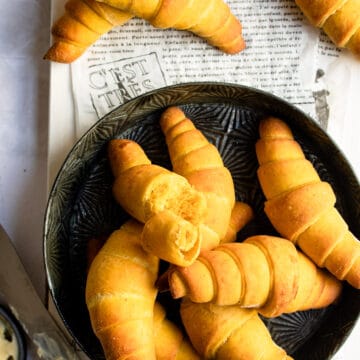 Pumpkin crescent rolls on a black plate.