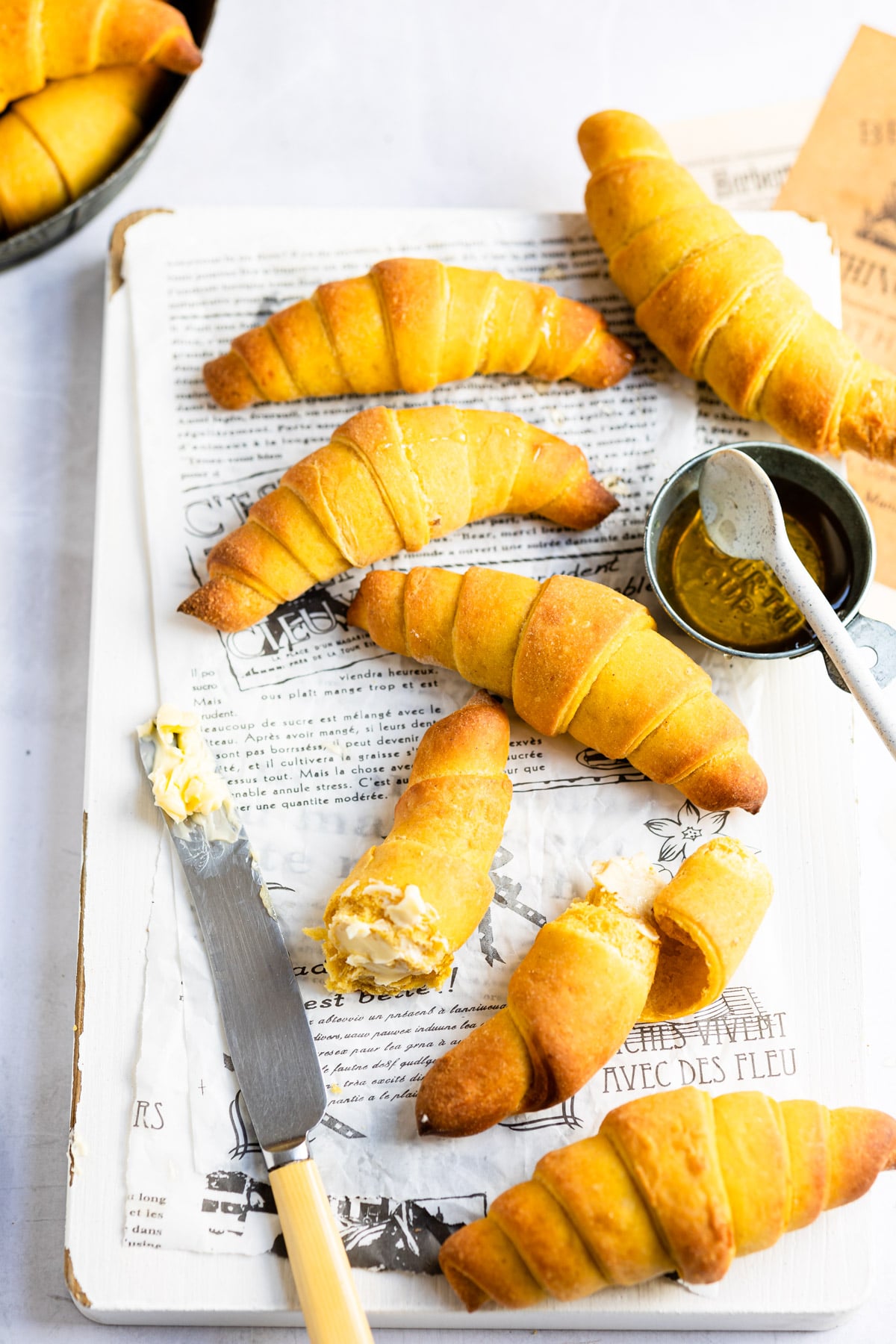 Pumpkin crescent rolls next to a knife with butter on it. 