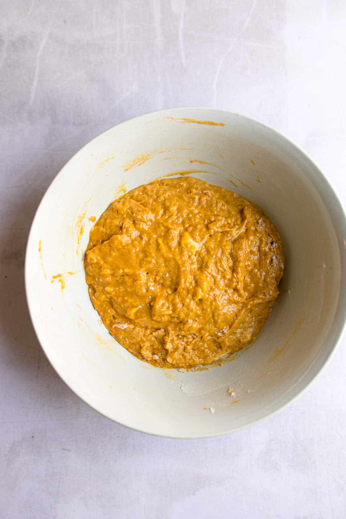 Pumpkin dough in a white mixing bowl. 