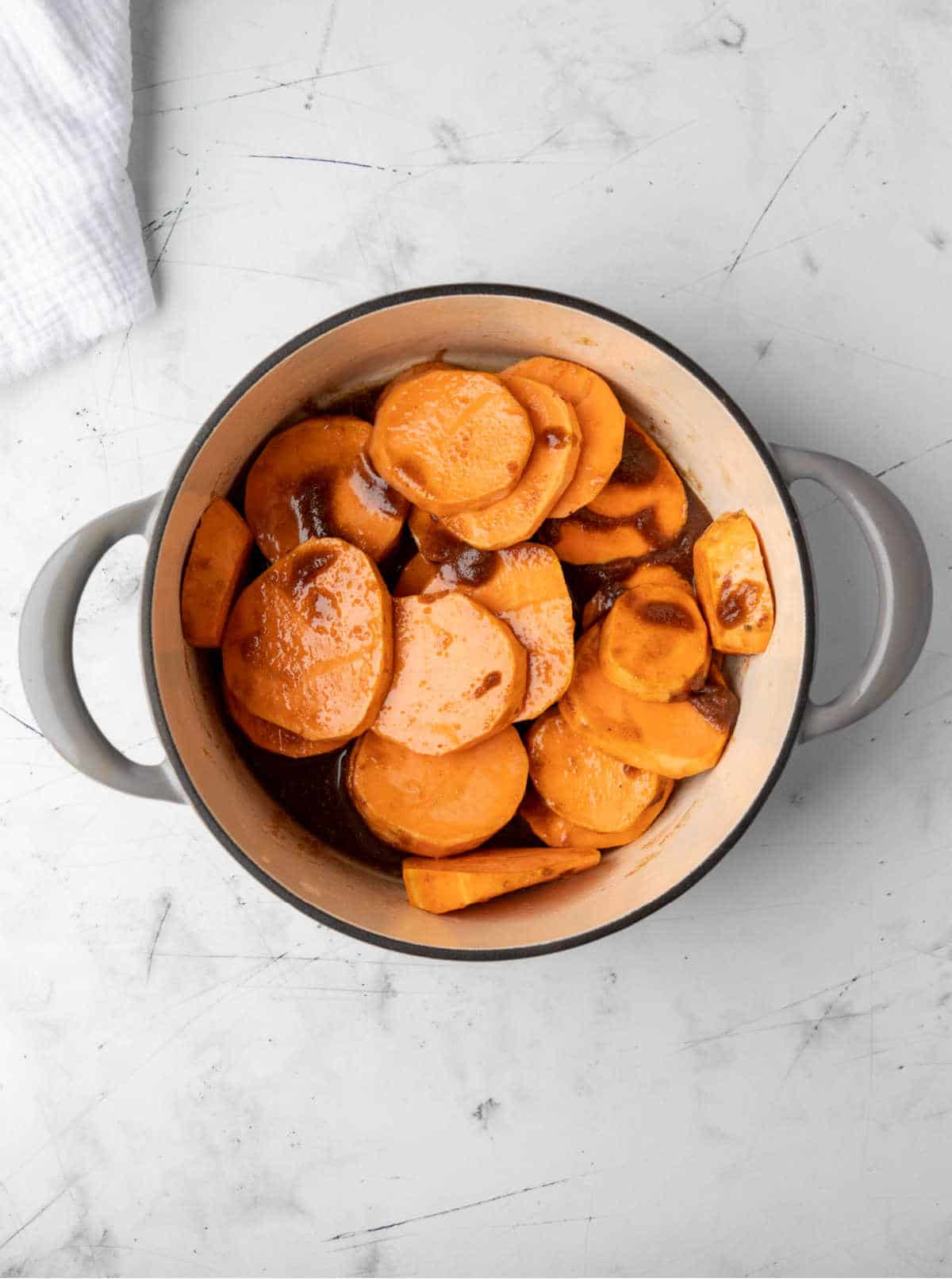 Sliced sweet potatoes and butter and sugar mixture in a Dutch oven.