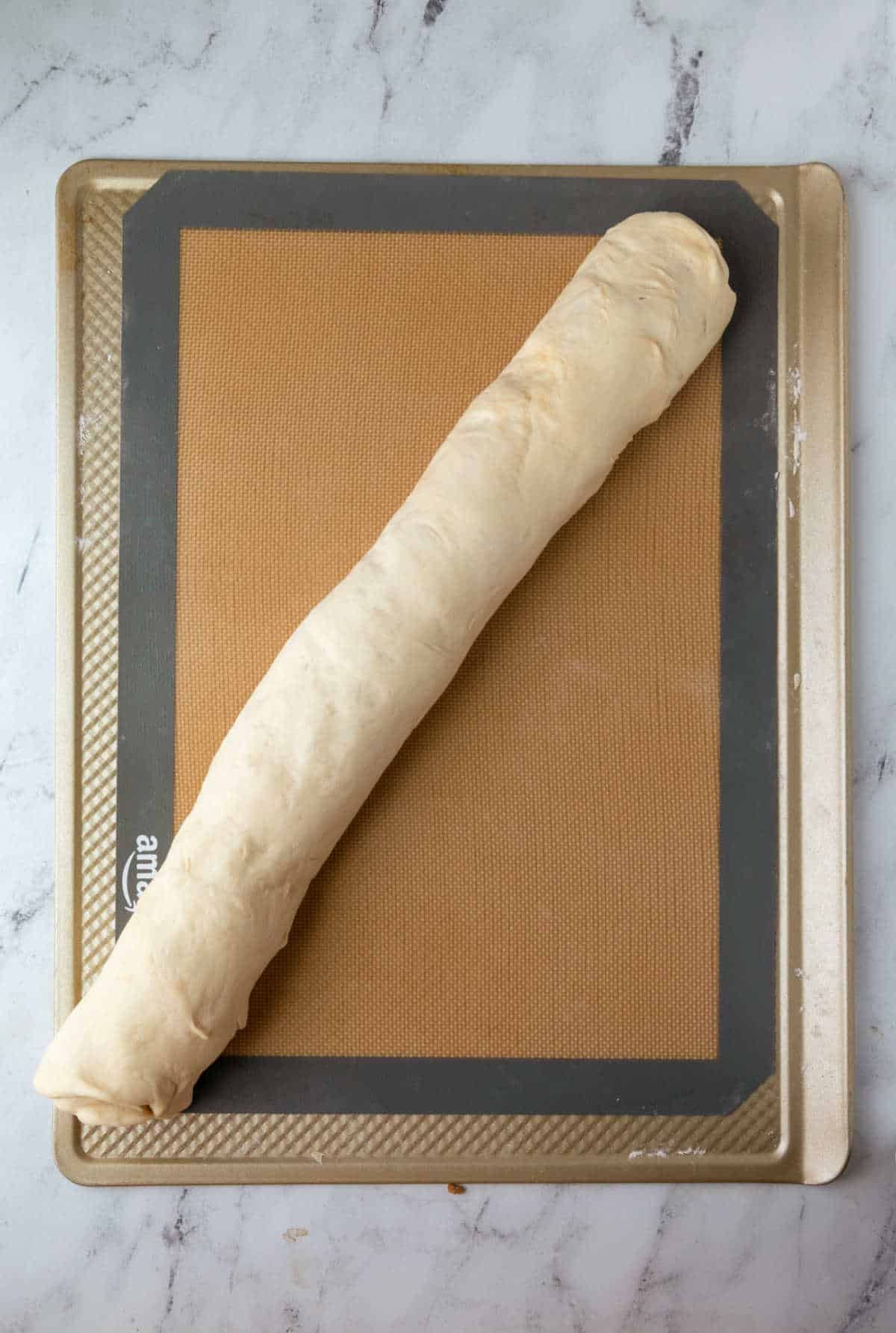 Maple sticky bun dough rolled up into a log.