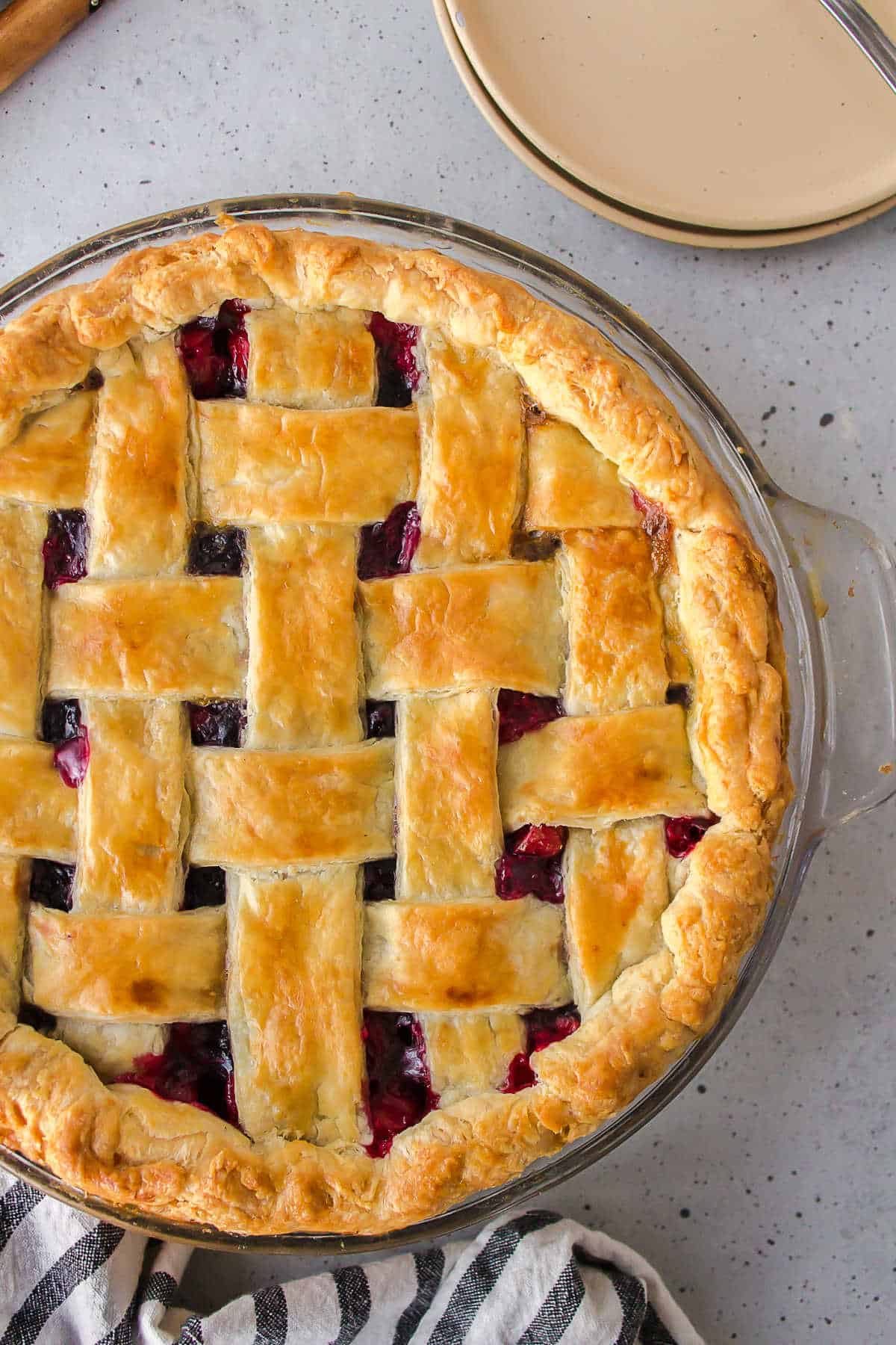 Baked pie next to a stack of plates. 