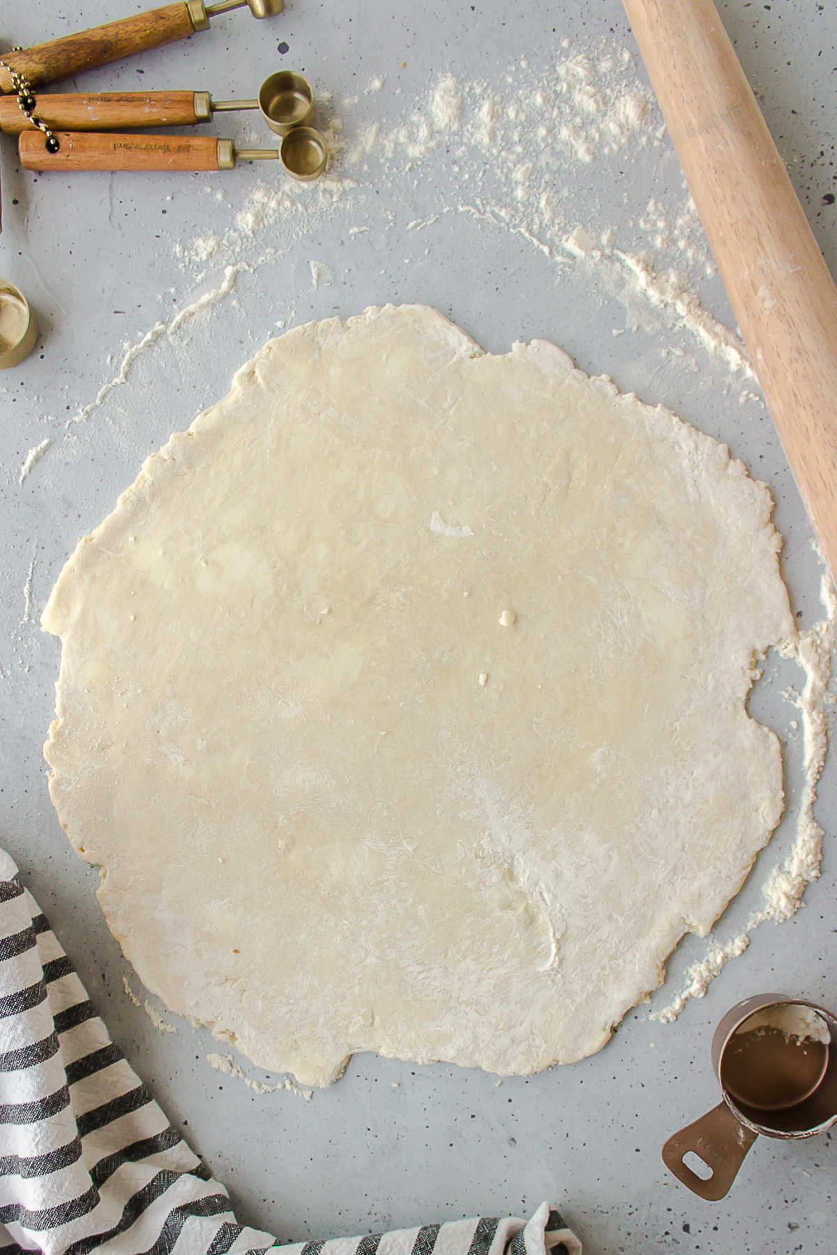 Rolled out pie dough next to a rolling pin. 