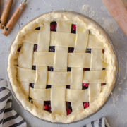 Unbaked lattice pie next to a rolling pin.