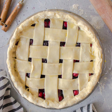 Unbaked lattice pie next to a rolling pin.