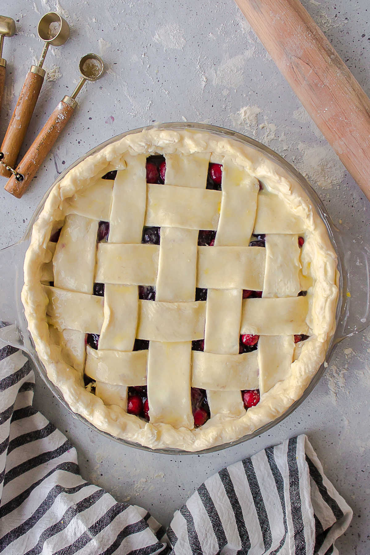 Unbaked lattice pie next to a rolling pin. 