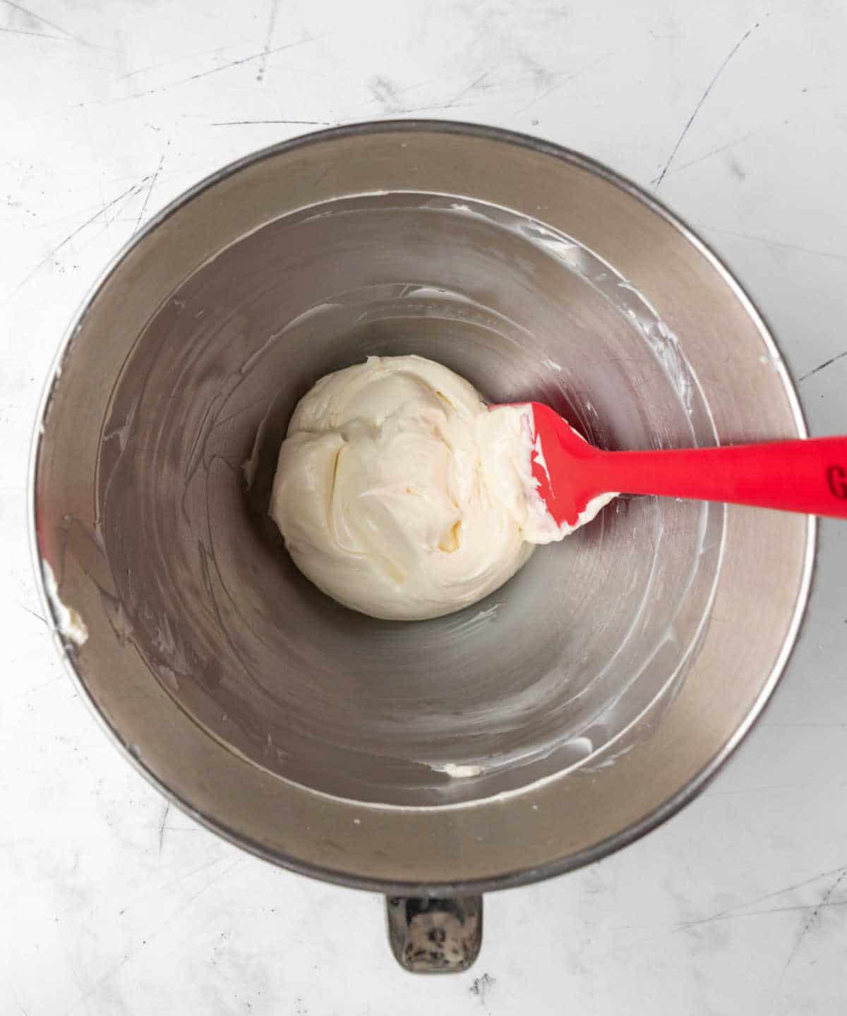 Beaten cream cheese and butter in a silver mixing bowl. 