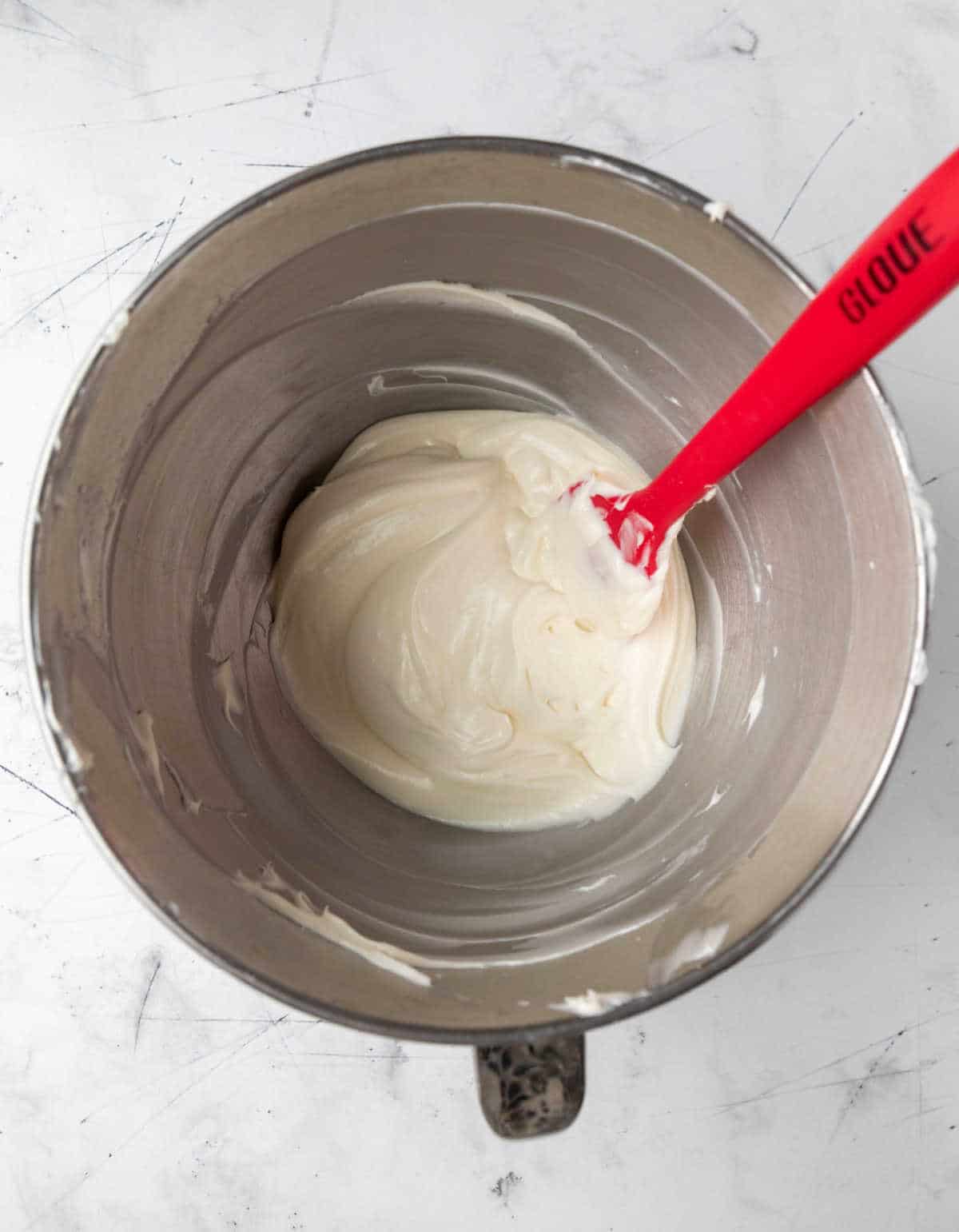 Cream cheese frosting in a silver mixing bowl. 