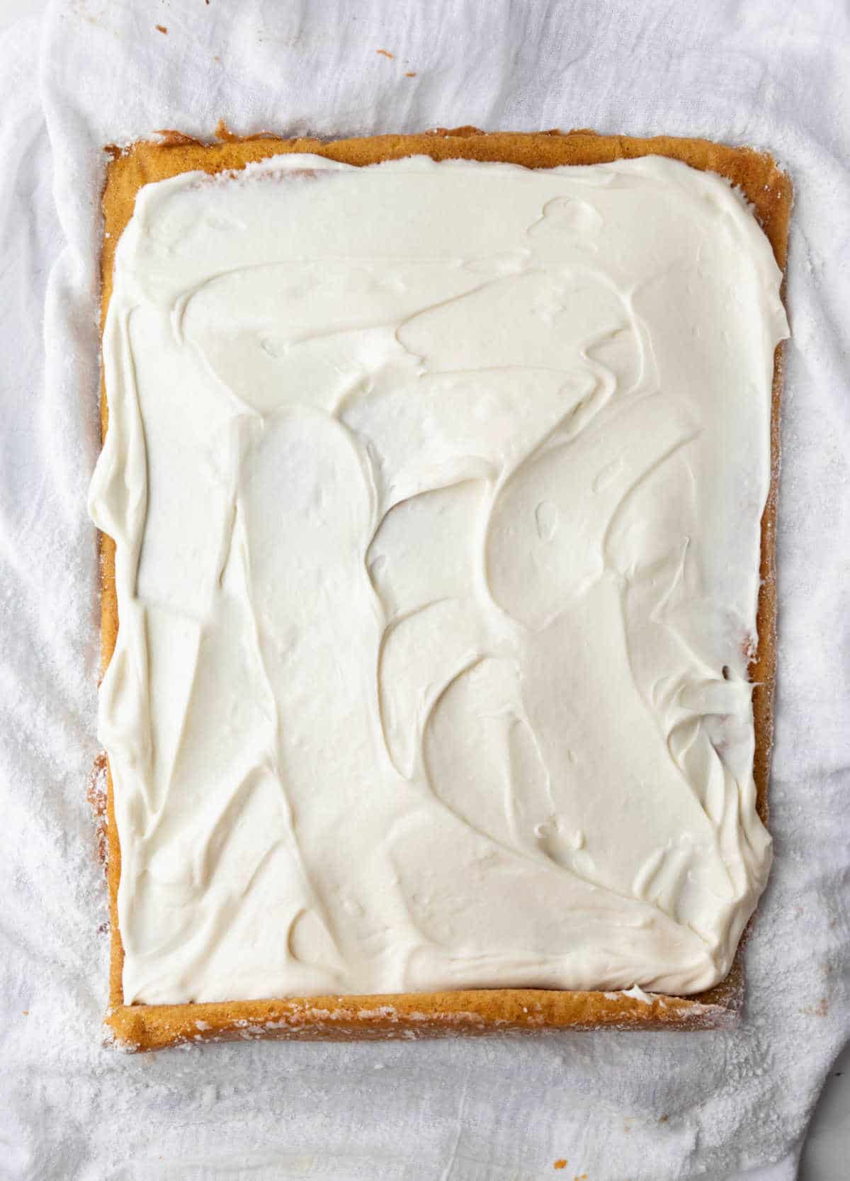 Cream cheese frosting on an unrolled pumpkin roll. 