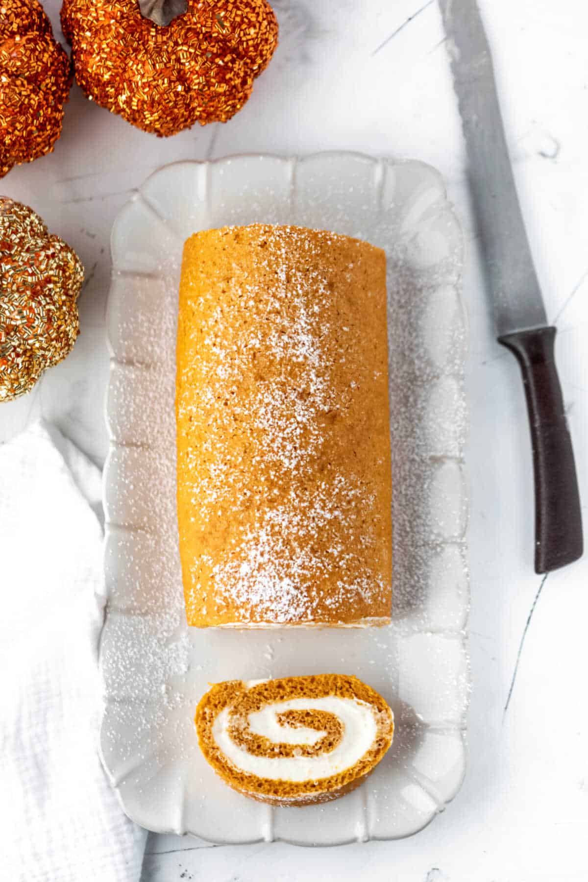 Pumpkin cake roll with a slice cut off. 