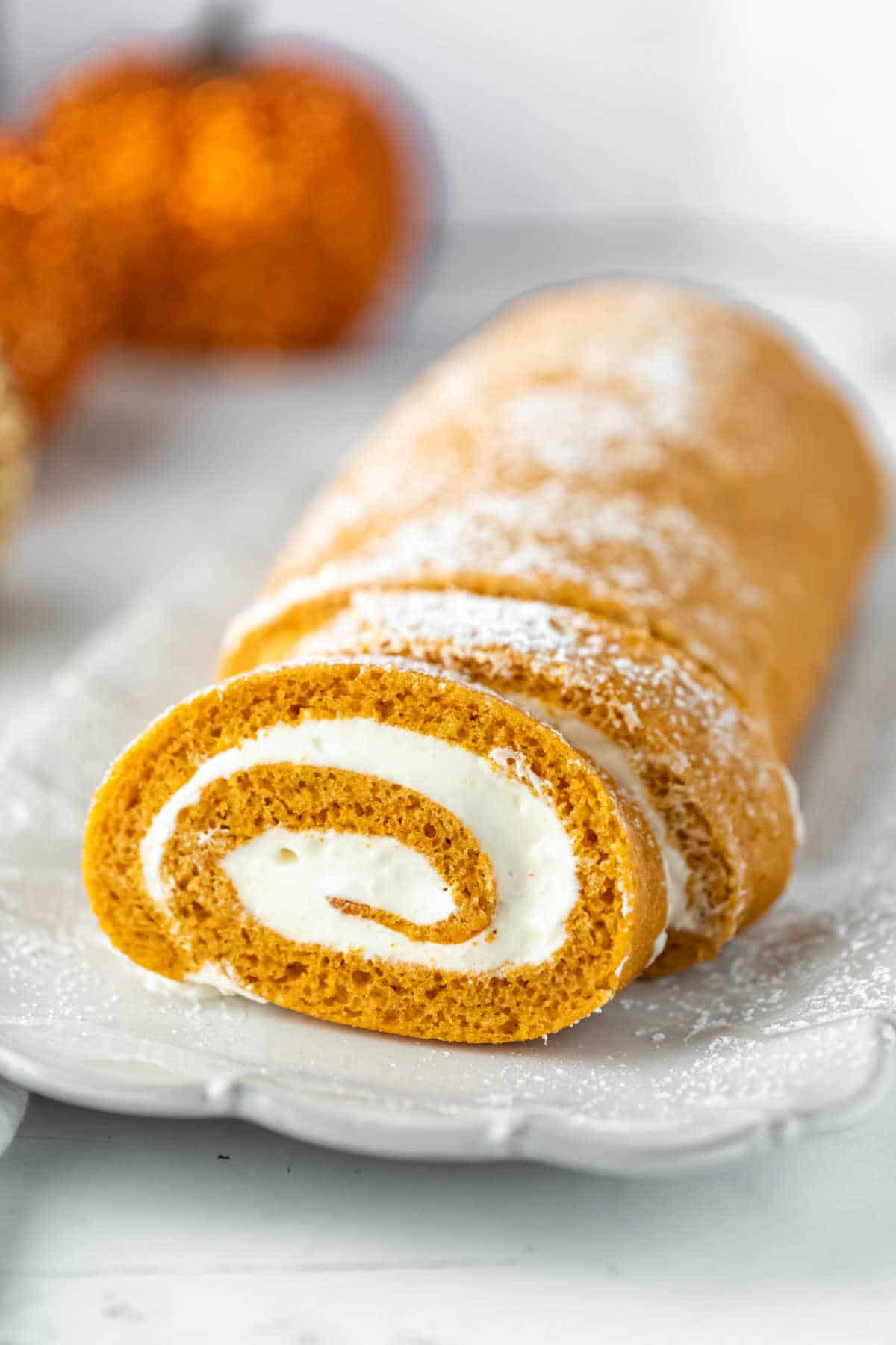 Pumpkin cake roll at an angle on a white platter. 