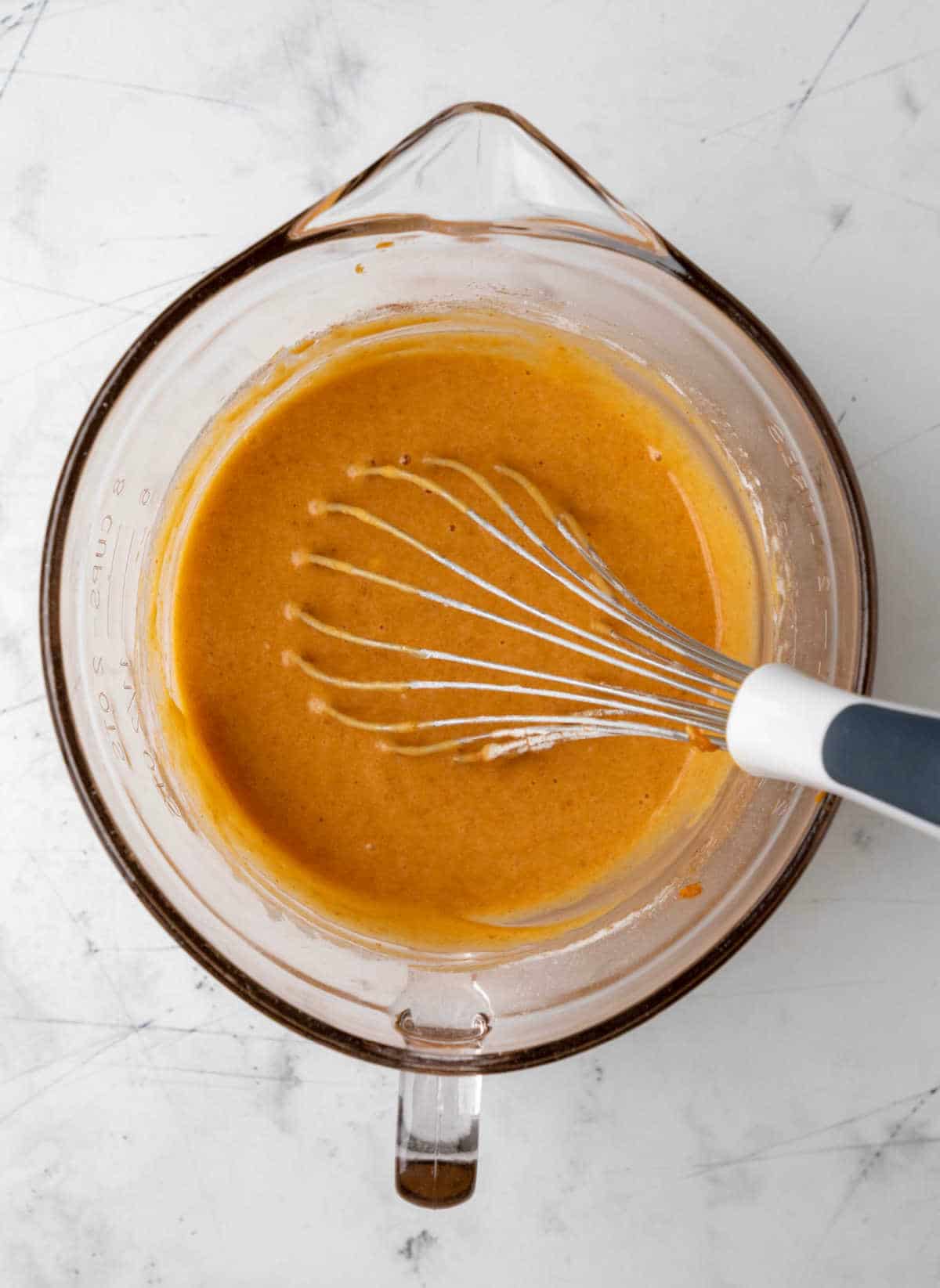 Pumpkin cake batter in a glass mixing bowl.