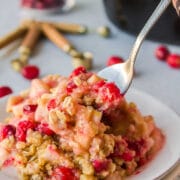 Spoon taking a bite of cranberry apple crisp.