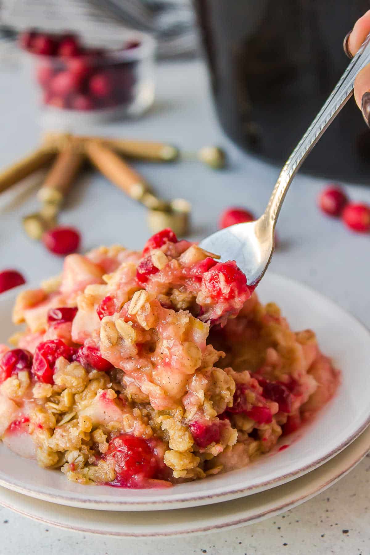 Spoon taking a bite of cranberry apple crisp. 