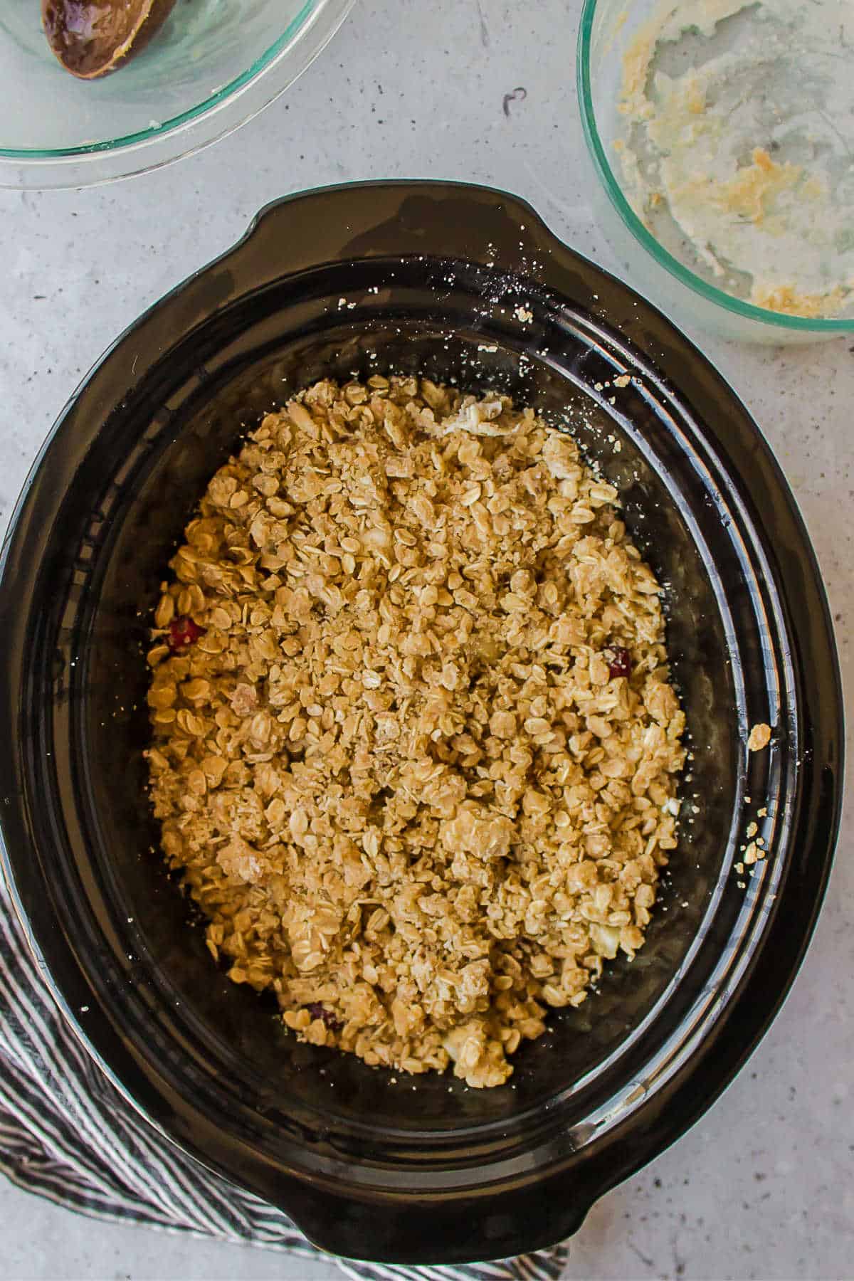 Uncooked cranberry apple crisp in a slow cooker insert. 