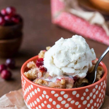 Dish of cranberry apple crisp with a scoop of vanilla ice cream on top.