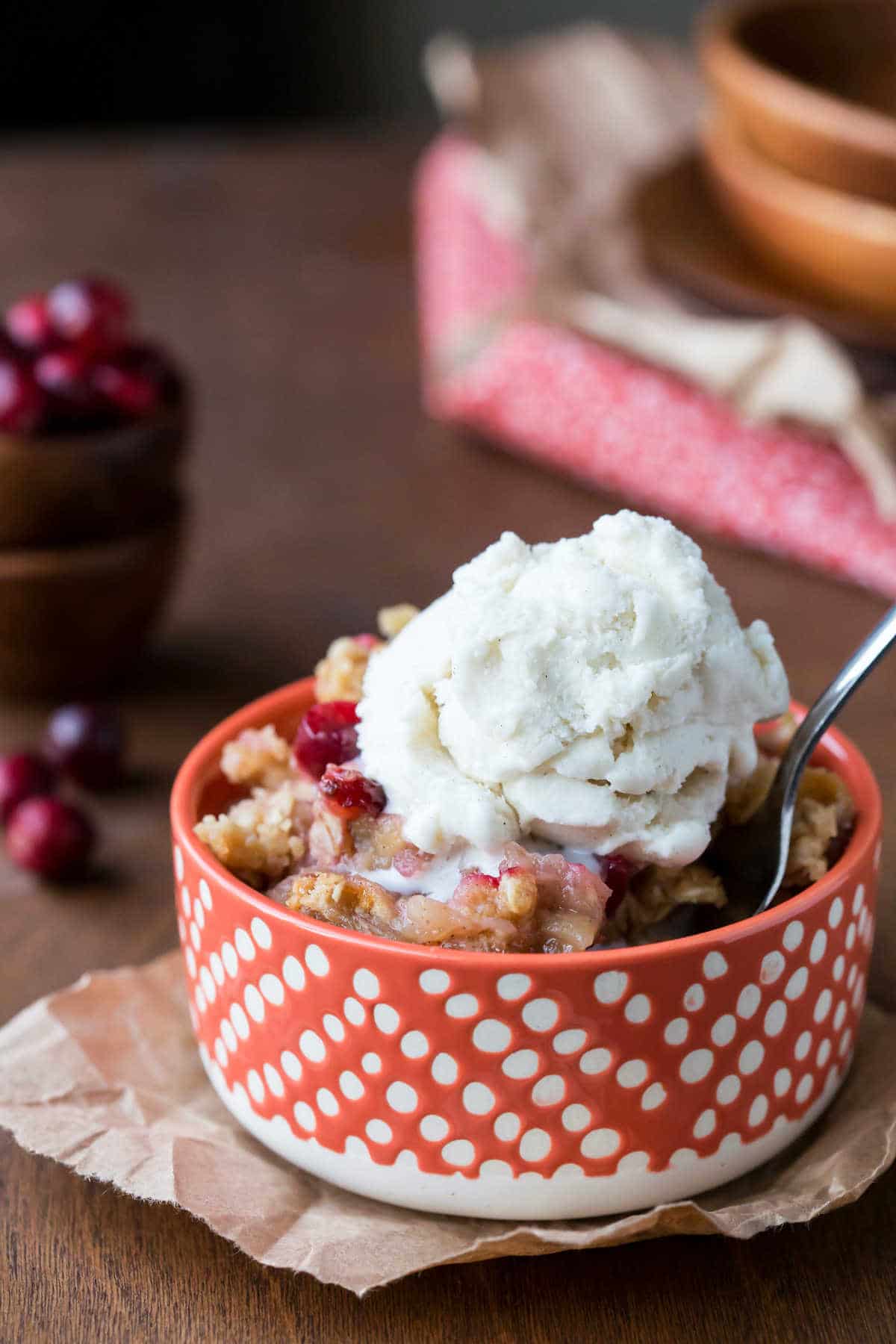 Dish of cranberry apple crisp with a scoop of vanilla ice cream on top. 