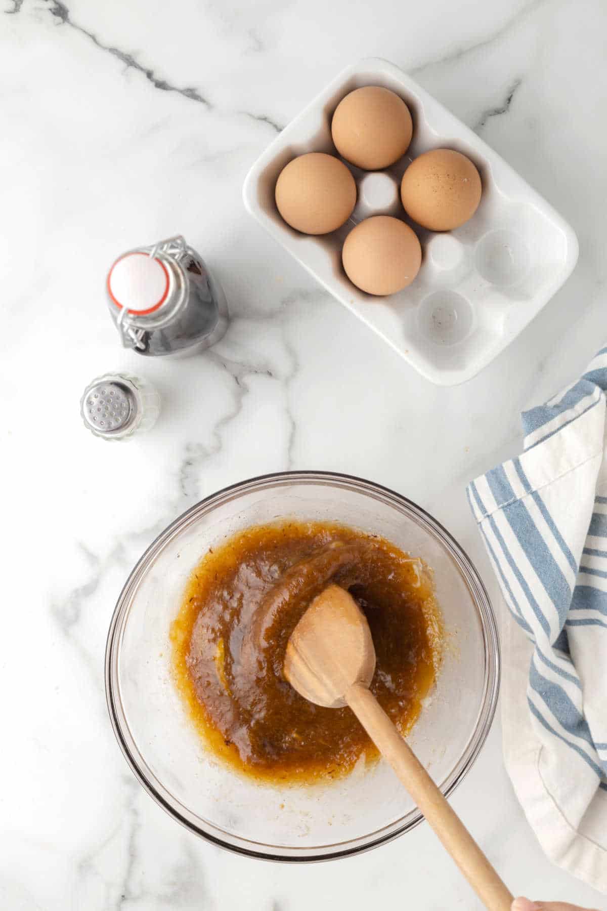 Brown sugar melted butter and eggs mixed together in a glass bowl. 