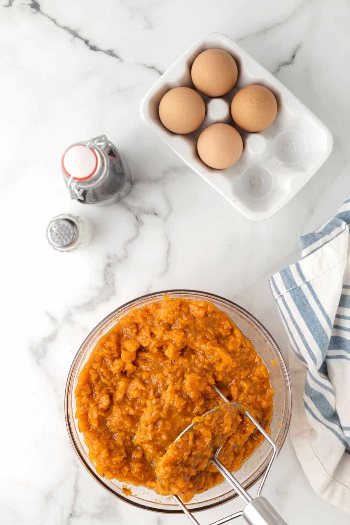 Mashed sweet potato in a glass mixing bowl. 