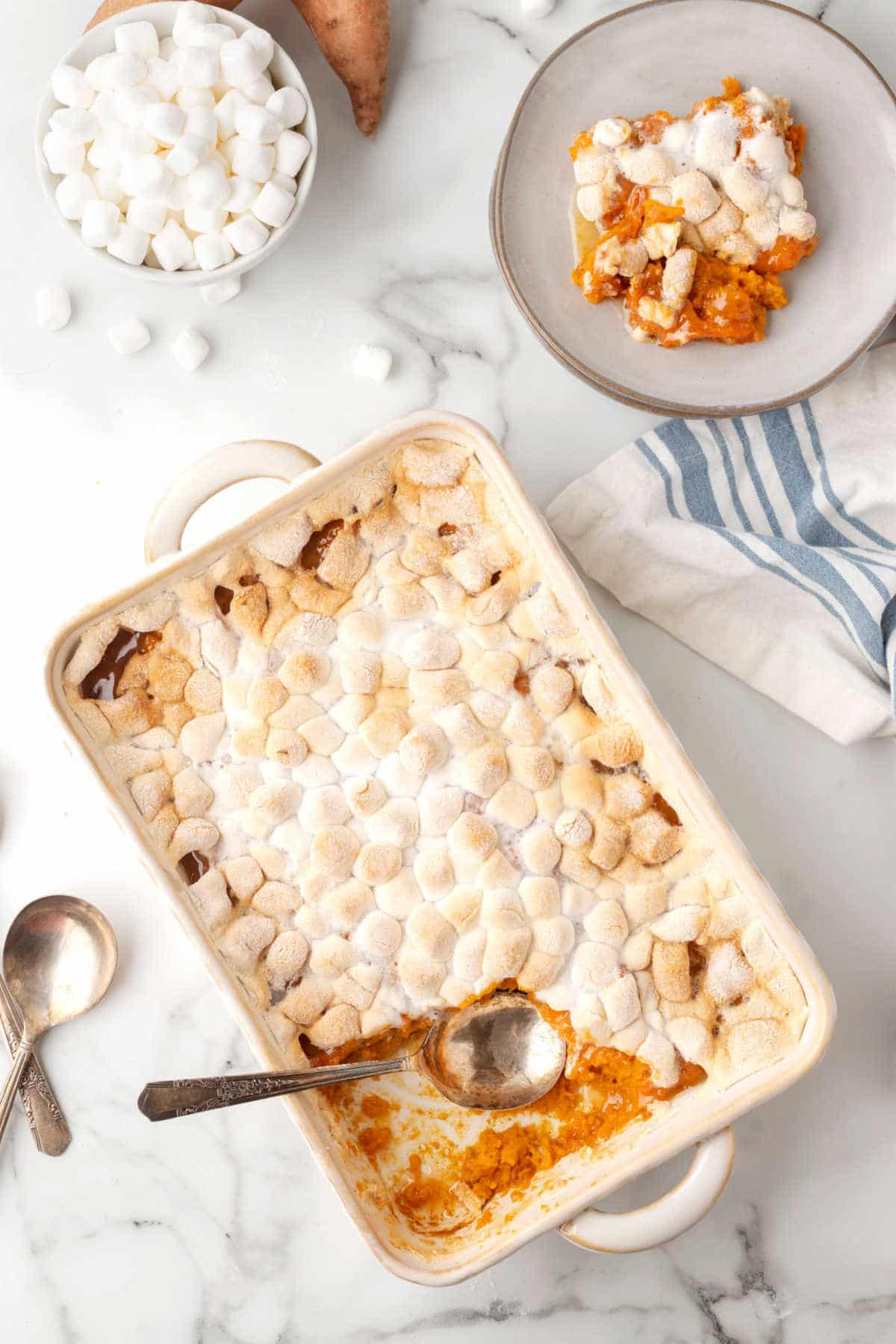 Dish of sweet potato casserole next to a plate of sweet potato casserole. 