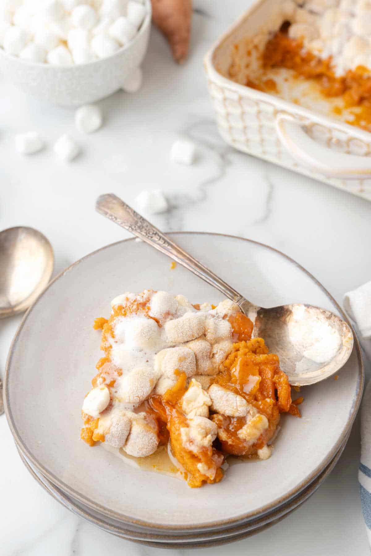 A silver spoon on a plate of sweet potato casserole. 