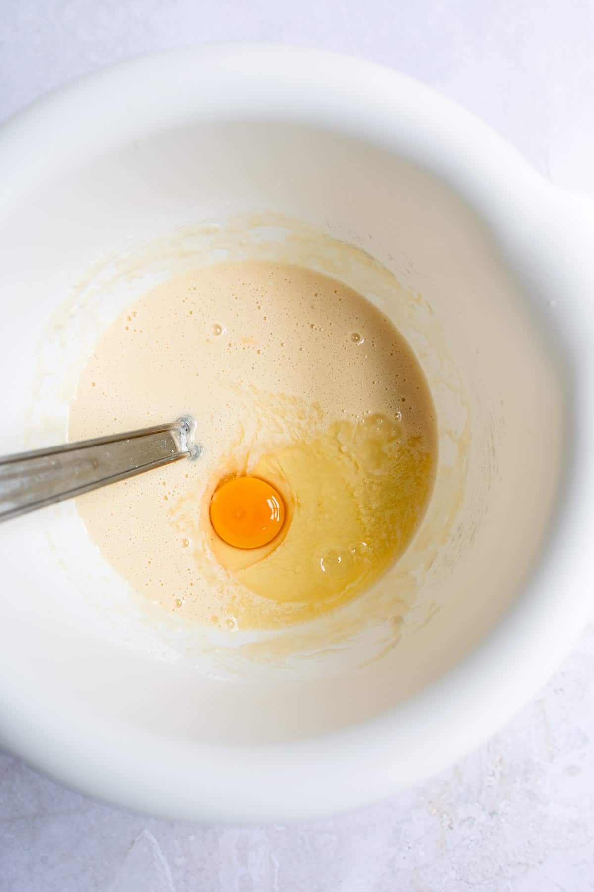 Egg in batter in a white mixing bowl.