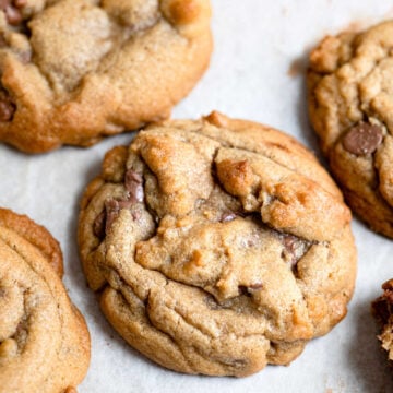 Bakery style chocolate chip cookies on a piece of parchment paper.
