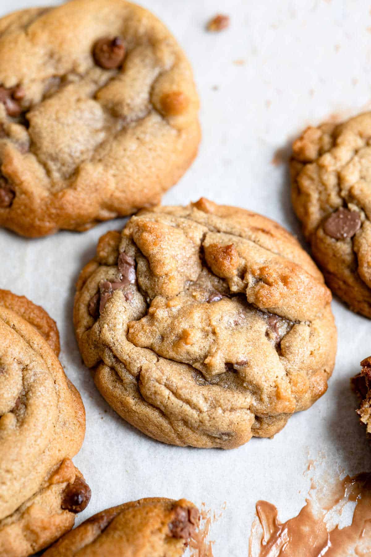 Bakery style chocolate chip cookies on a piece of parchment paper.