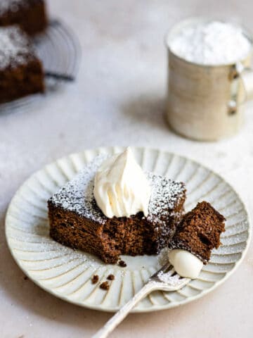 Piece of gingerbread topped with powdered sugar and whipped cream.