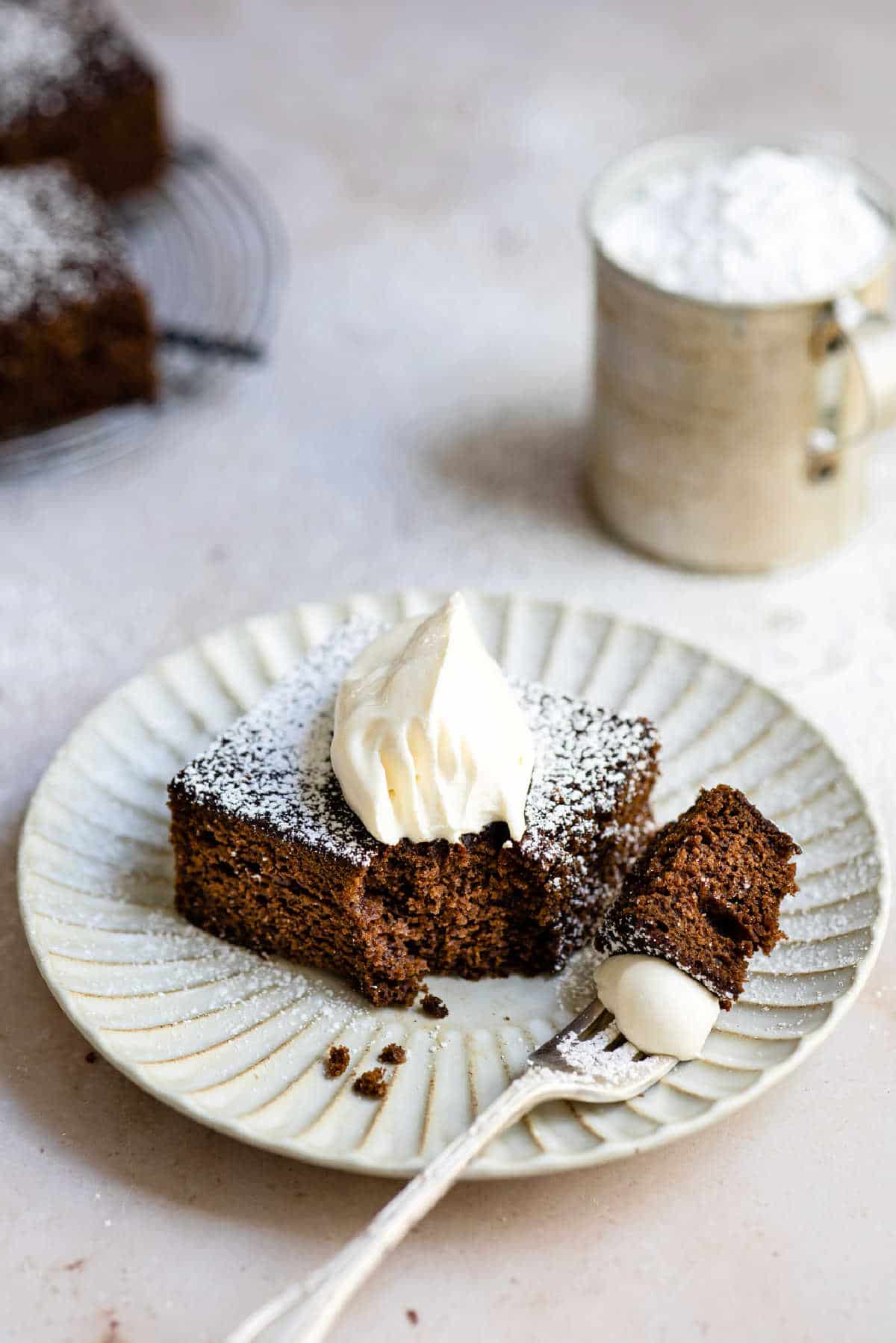 Piece of gingerbread topped with powdered sugar and whipped cream. 