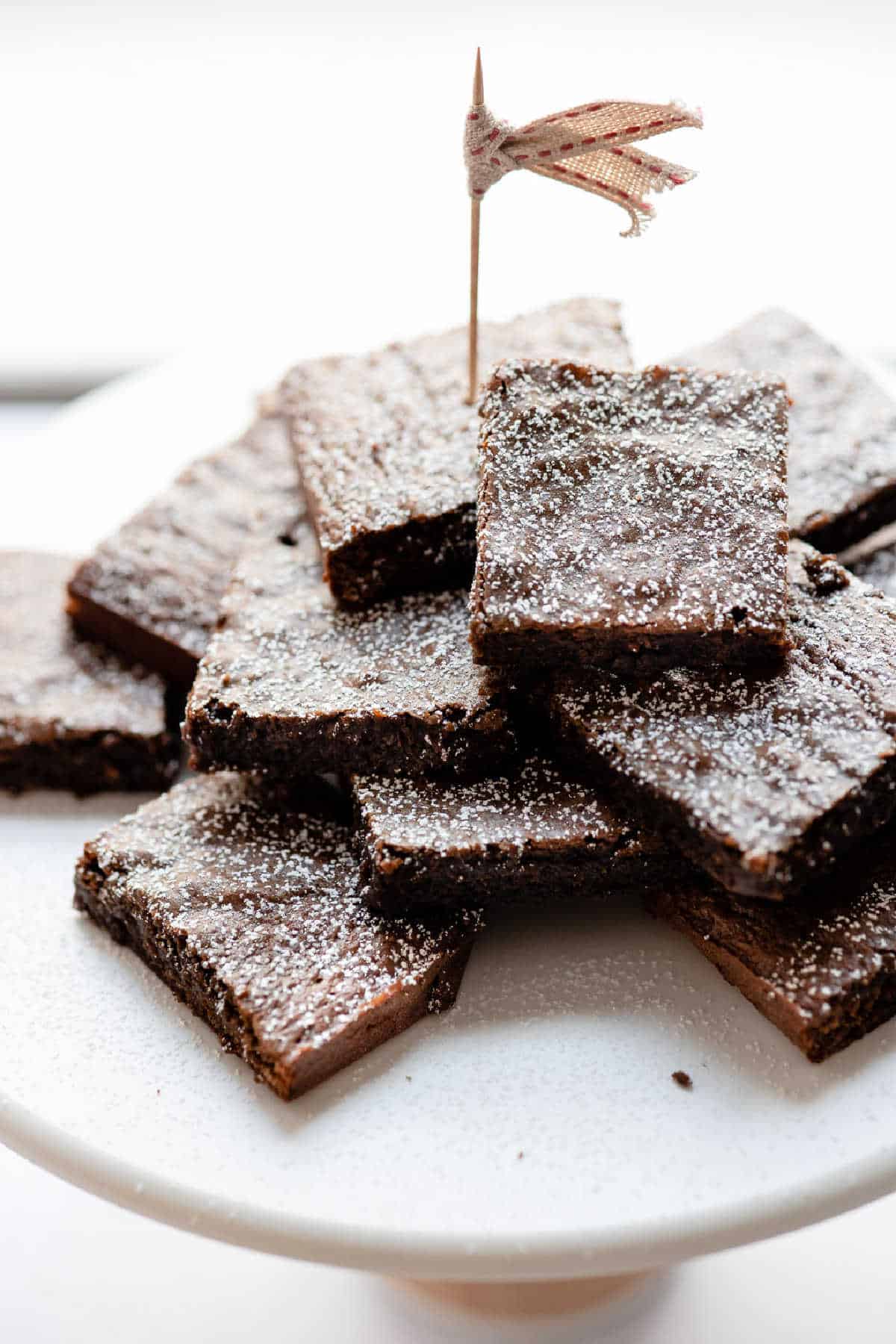 A stack of gingerbread brownies on a marble cake stand.