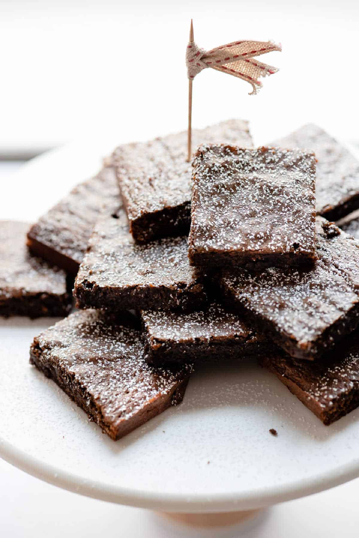 A stack of gingerbread brownies on a marble cake stand. 