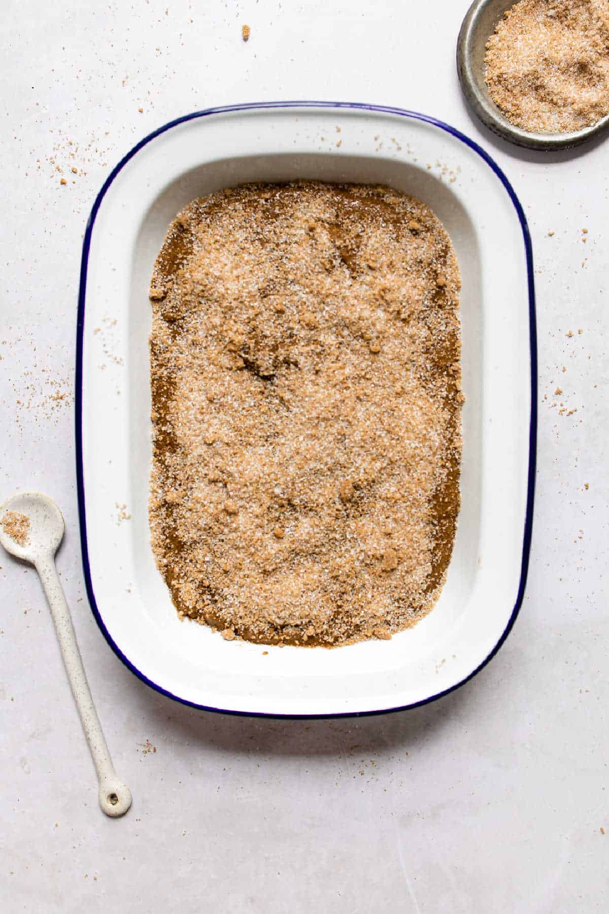 Cinnamon sugar over gingerbread pudding cake batter in a cake pan.