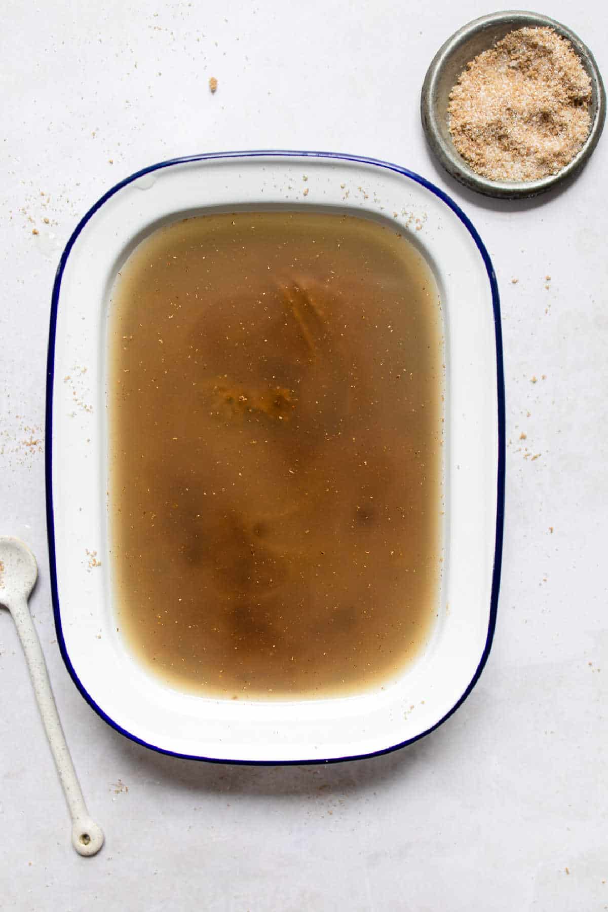 Apple cider over gingerbread pudding cake batter in a cake pan.