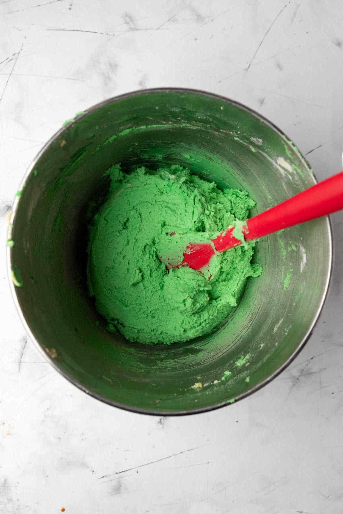 Grinch cookie batter in a silver mixing bowl. 