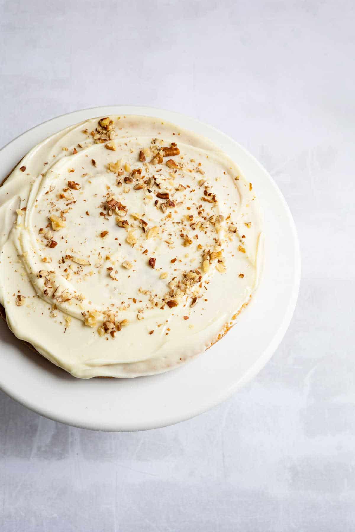 Top down photo of an Italian cream cake with pecans sprinkled on top. 
