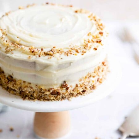 Italian cream cake on a cake stand next to a cake spade.