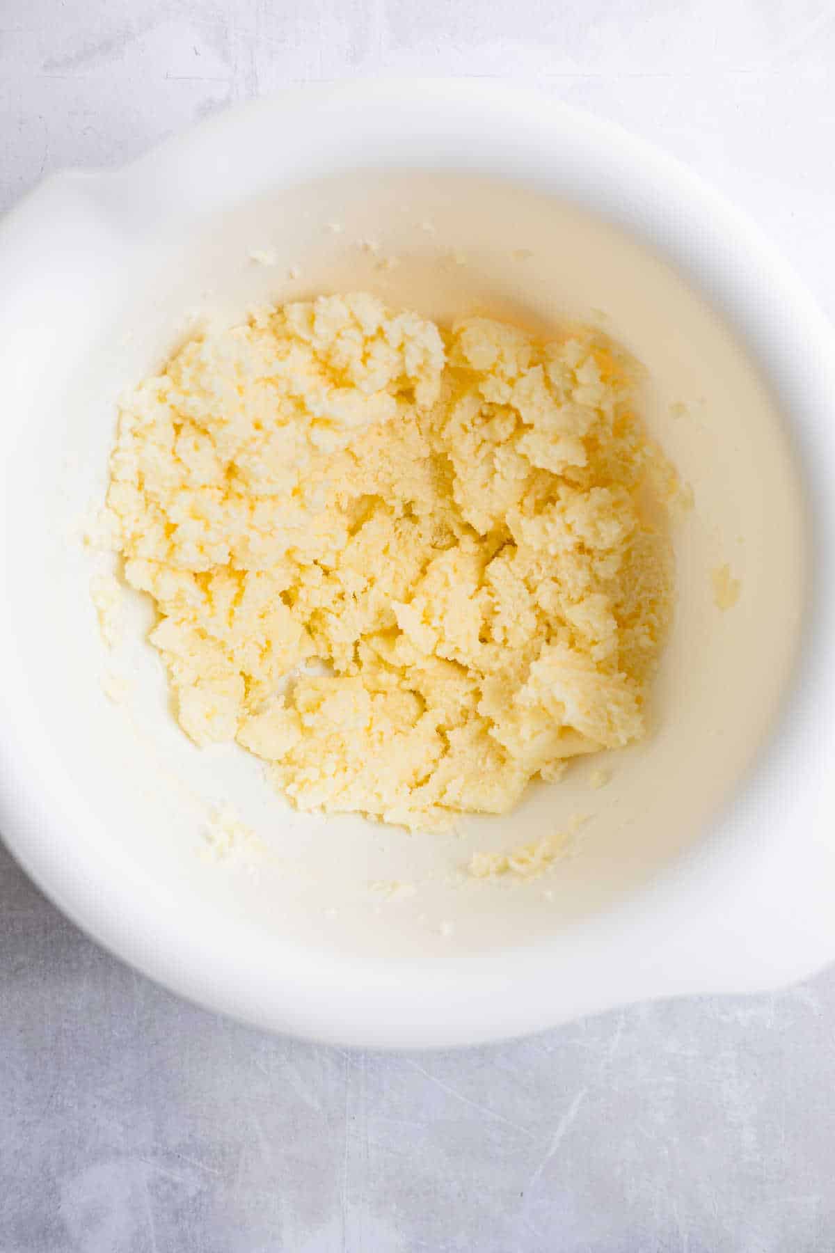 Eggs sugar and creamed butter mixture in a white mixing bowl. 