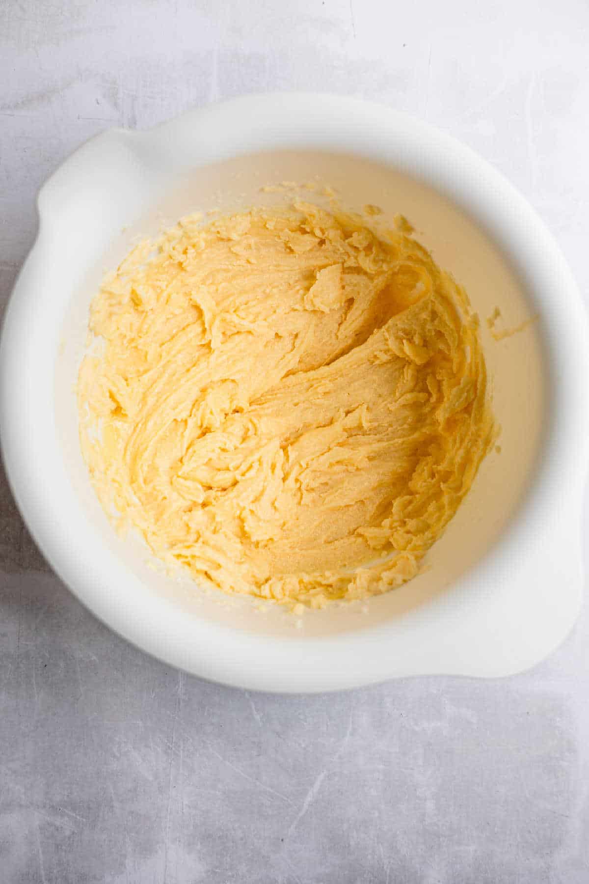 Eggs and creamed sugar and butter mixture in a white mixing bowl. 